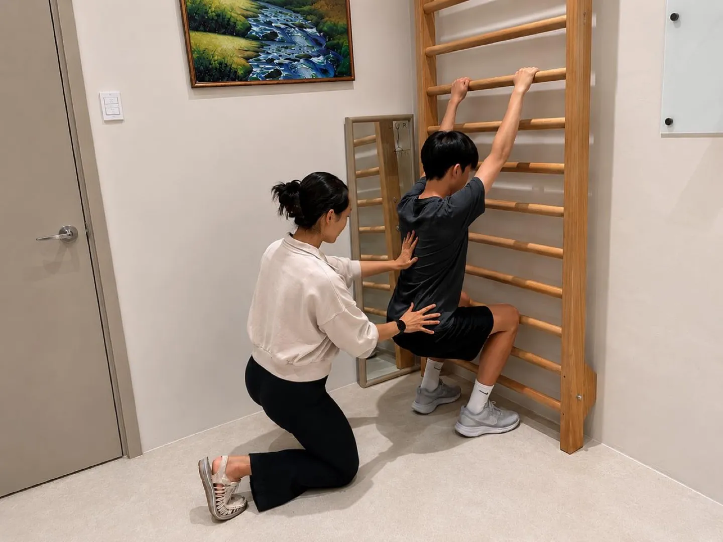 A Goji physiotherapist guiding a young person through Schroth Method scoliosis exercises at the wall bars.